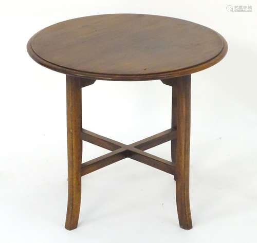 An early 20thC occasional table with a circular mahogany top above four swept legs and cross