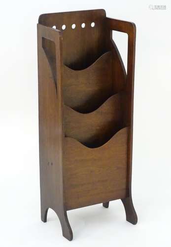 An Arts & Crafts Glasgow school oak magazine rack with pierced holes to the frame and with three