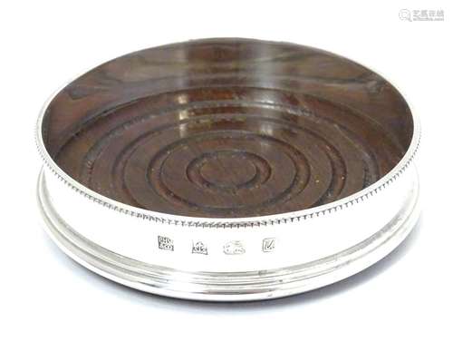 A silver wine coaster with turned wooden base, hallmarked Birmingham 1969, maker P H Vogel & Co.