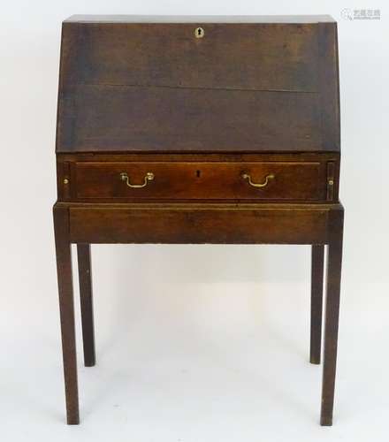 An 18thC oak bureau on stand, with a fall opening to show graduated drawers and a central door,