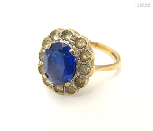 A 9ct gold ring set with central oval facet cut blue stone bordered by 12 white stones. The