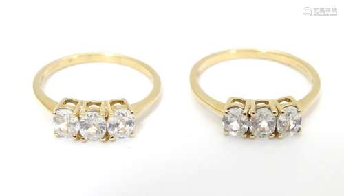 Two 10ct gold rings each set with trio of white stones. Ring sizes approx size O and size R (2)