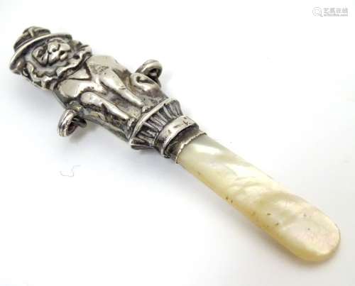 A silver rattle handle with comical lion to centre and mother of pearl teether. Hallmarked