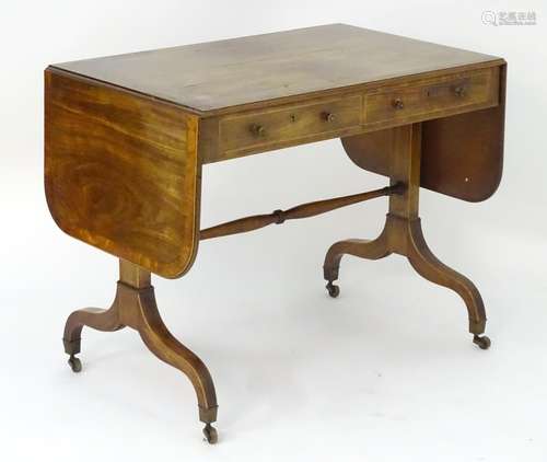 An early 19thC mahogany sofa table with cross banded top and drop flaps, decorative stringing and