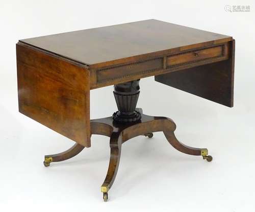 A Regency mahogany sofa table with two flaps, two short drawers and two sham drawers above a