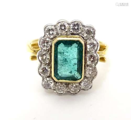 An 18ct gold ring set with central emerald bordered by 14 diamonds. the whole setting 3/4