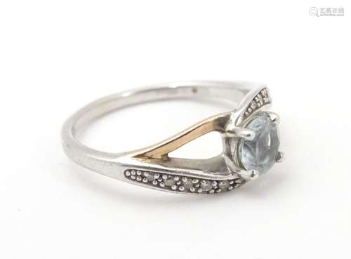 A silver ring with 9ct gold detail set with central white stone flanked by bands of chip set