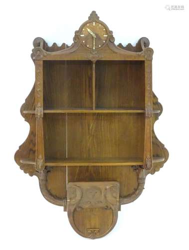 A c.1936 oak hanging shelf with a carved frame, walnut clock face, graduated shelves and a carved