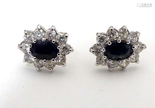 A pair of 9ct gold stud earrings set with blue and white stones in a cluster setting. The setting