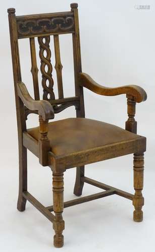 An early 20thC oak open armchair with a Celtic style carved top rail and back ress, having swept