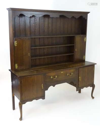 An early 20thC oak dresser with a moulded cornice above a shaped frieze and plate rack flanked by