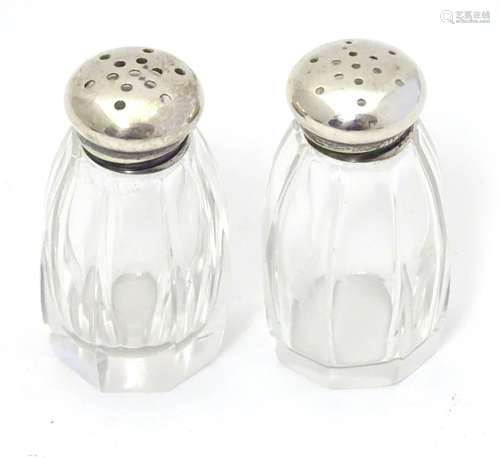 A pair of glass pepperettes with silver tops marked Sterling. Approx 2