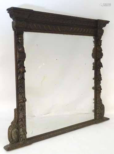 A late 19thC carved oak mirror with an ornately carved frame depicting foliage, fruit, caryatids and