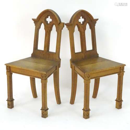 A pair of mid 19thC oak hall chairs with pointed pediments, pierced decoration and carved