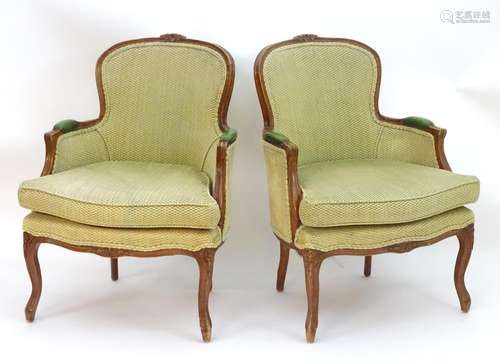 A pair of French Louis XV style armchairs with moulded frames, carved cresting rails and leather