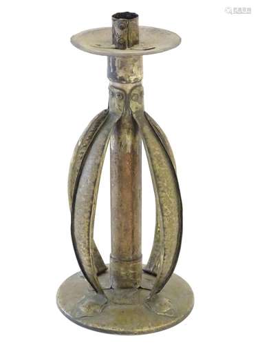 An Arts and Crafts copper and brass candlestick with a hammered finish and bowed strapwork supports,