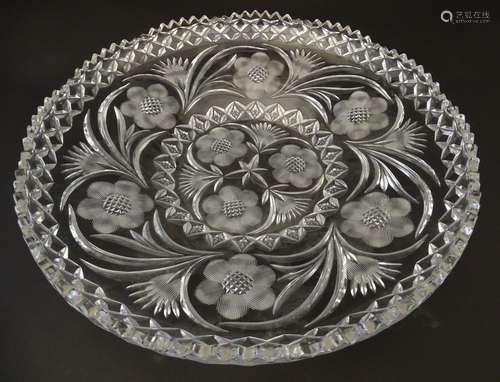 A large early 20thC cut glass charger, decorated with thistle, frond, star and rose cuts and diamond