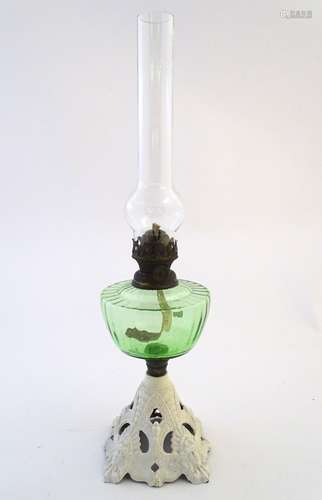 An early-20thC oil table lamp, with Falk's burner and green glass reservoir, standing on a white