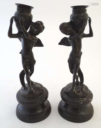 A pair of 20thC figural spelter candlesticks, each formed as an angel holding a vase. Approx. 11