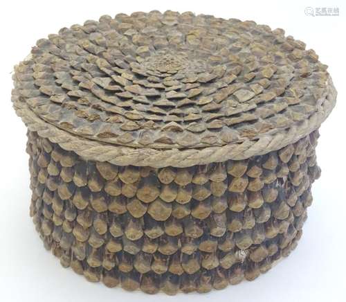 A naive circular box decorated with layered pine cone scales. Approx. 4 1/4