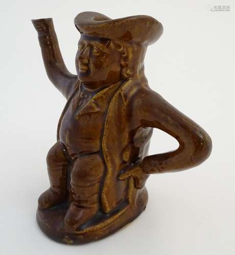 A treacle glazed Toby jug teapot formed as a seated man, his arms forming the handle and spout.