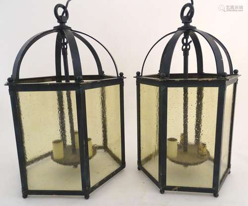 A graduated pair of bronze pendant hall lanterns, of hexagonal form with glazed panels and black