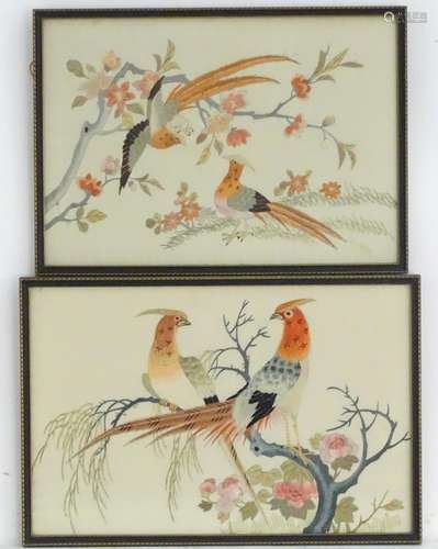 Two oriental silk embroideries depicting stylised golden pheasant birds perched on branches, with