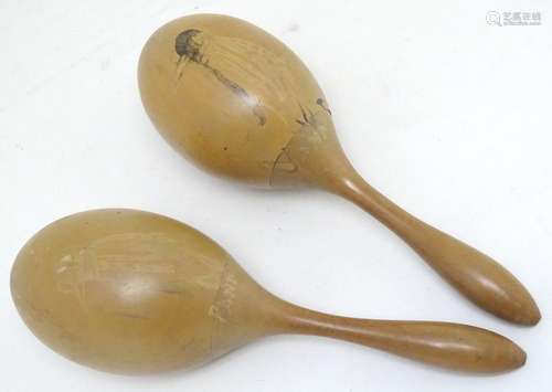 A pair of wooden maracas with naive decoration depicting a stylised bird, Panama souvenir. Approx.