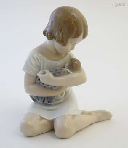 A Royal Copenhagen model of a seated girl with a doll, model no. 1938, designed by Ada Bonfils.