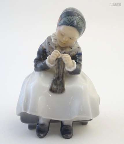 A Royal Copenhagen figure of a seated Amager girl knitting, model no. 1314, designed by Lotte