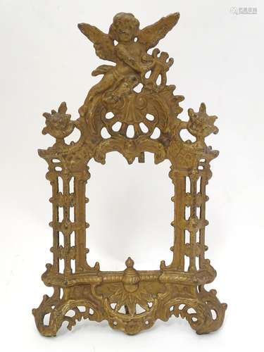 An early 20thC cast metal frame of stylised architectural form surmounted by a putto with a lyre.