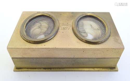 An unusual Victorian gilt metal box set with twin oval locket sections to lid containing locks of