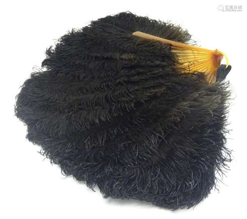 An early 20thC ostrich feather fan, with 18 sticks, the front stick with white metal detail set with