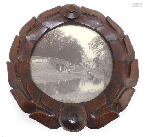 A 20thC circular carved mahogany frame of stylised wreath form, displaying a black and white