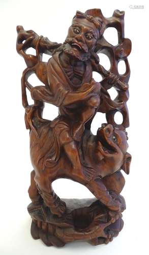 An Oriental hardwood carving depicting a figure and a beast. Approx. 12