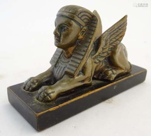 A 20thC paperweight formed as a winged sphinx with the head of a pharaoh on a rectangular wooden