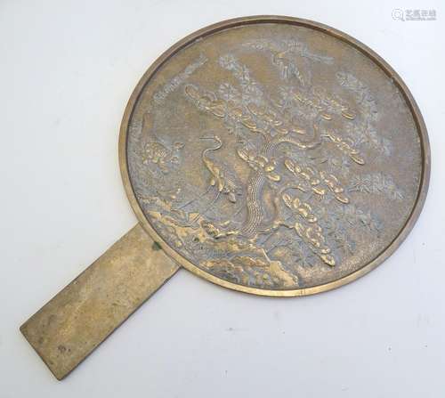 A Japanese kagami hand mirror decorated in relief with cranes, tortoises, a pine tree and bamboo.