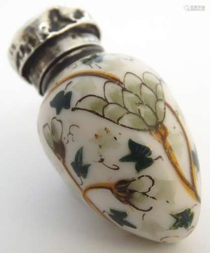 A 19th / 20thC porcelain scent bottle with a silver top, the body having scrolling foliate and