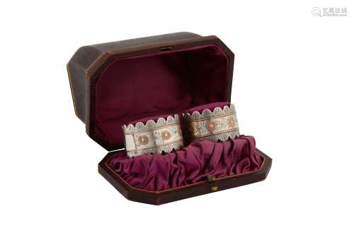 A cased pair of Victorian sterling silver and unmarked gold napkin rings, Birmingham 1885 by Colen