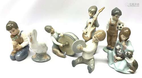 A group of Lladro and Nao figurines, comprising a trio modelled as boys playing instruments, boy wi