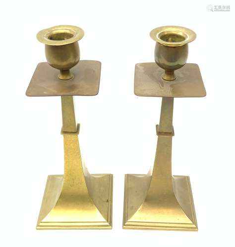 A pair of Aesthetic movement brass candlesticks, the square stepped bases leading to a tapering stem