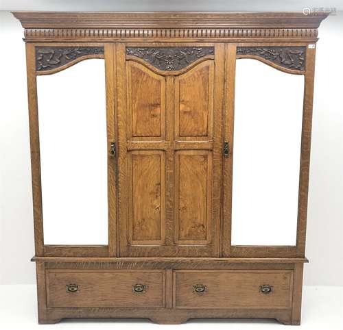 Early 20th century carved oak triple wardrobe, with two shaped mirrored doors, two drawers to base w