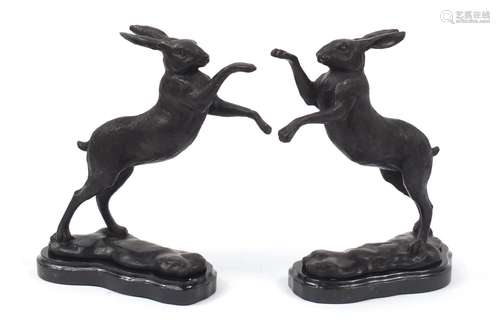 Pair of patinated bronze boxing hares raised on shaped black marble bases, each 29.5cm high : For