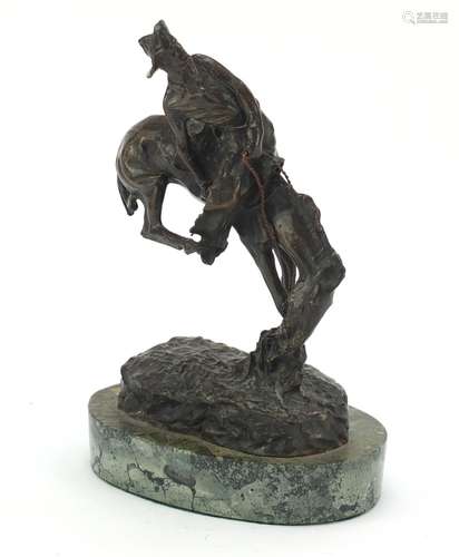 Patinated bronze figure of a cowboy on horseback in the style of Frederick Remington, raised on an