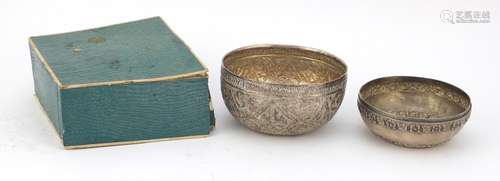 Two Thai silver coloured metal bowls embossed with flowers and foliage, housed in a velvet lined