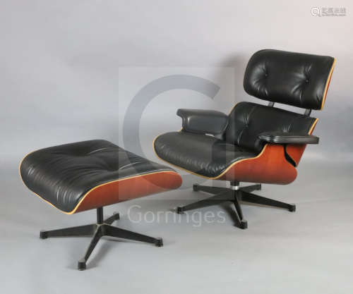 A Charles Eames cherrywood and black leather lounge chair with matching stool, made by Vitra,
