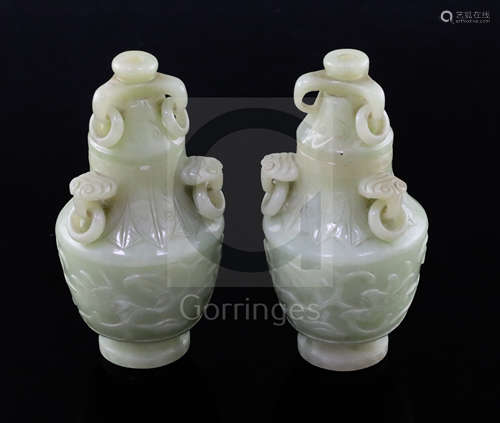 A pair of Chinese carved jade vases and covers, with ring handles and decorated with foliate motifs,