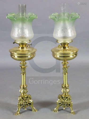 A pair of Victorian brass oil lamps, with green tinted frosted glass shades and foliate scroll