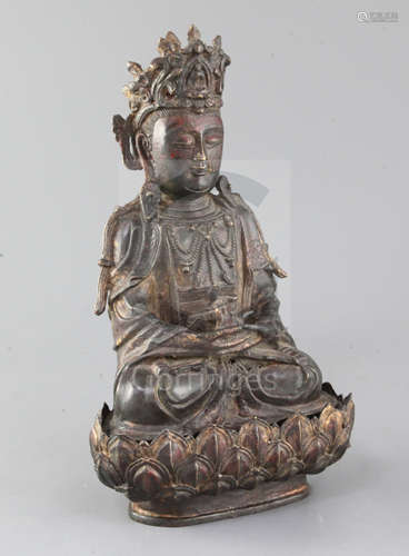 A Chinese lacquered bronze seated figure of Guanyin, possibly Ming dynasty, holding a ewer in both