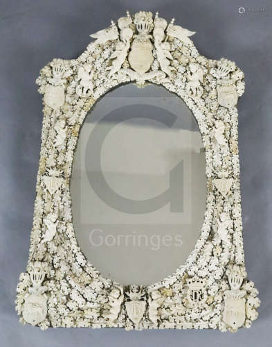 A 19th century Dieppe ivory wall ***ror, of arched rectangular form with oval plate, applied with
